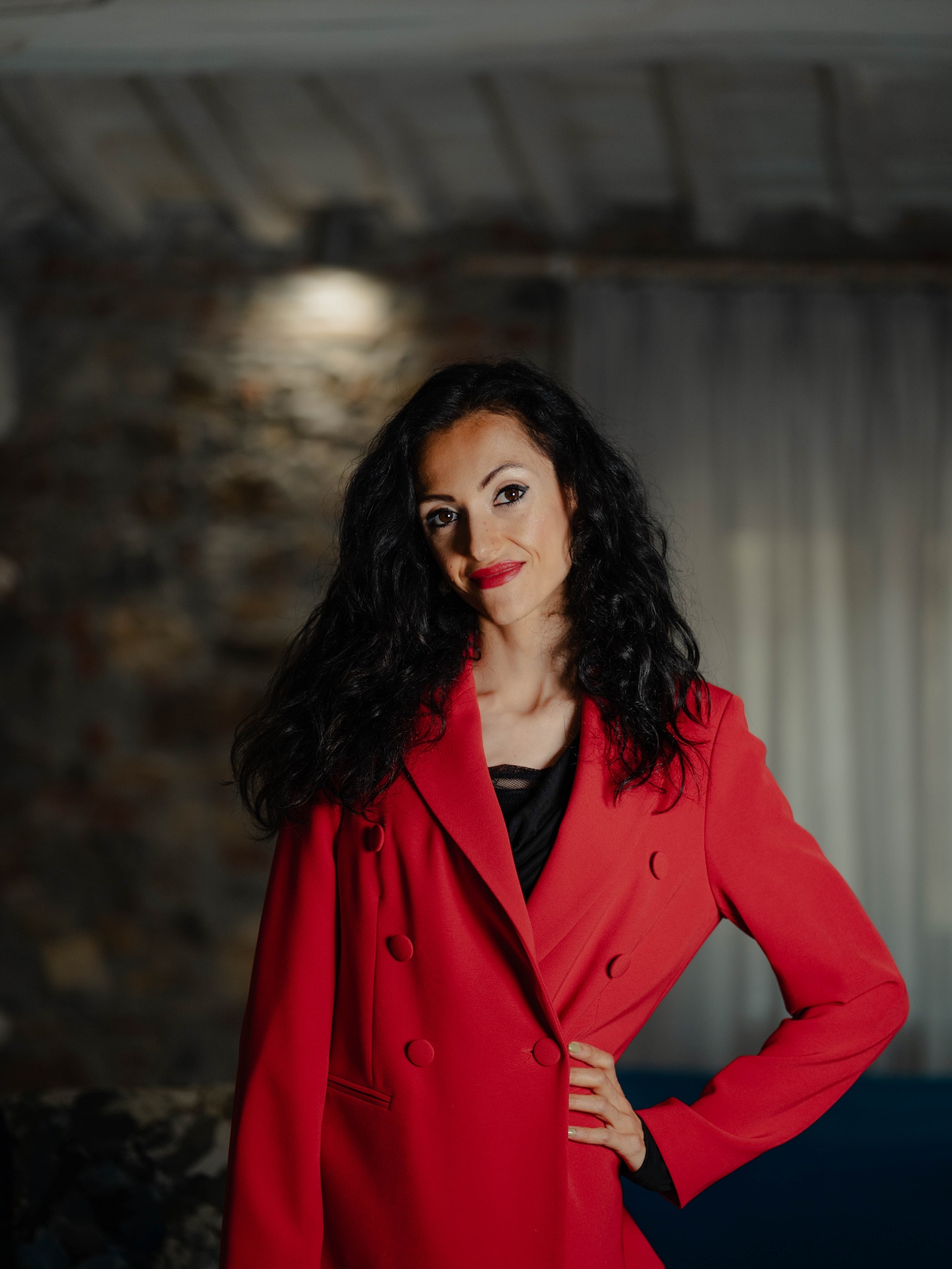 Ritratto di Giulia Trubiano in blazer rosso, mano sul fianco